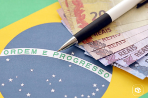Bandeira do Brasil com notas de real e caneta, simbolizando finanças e progresso.